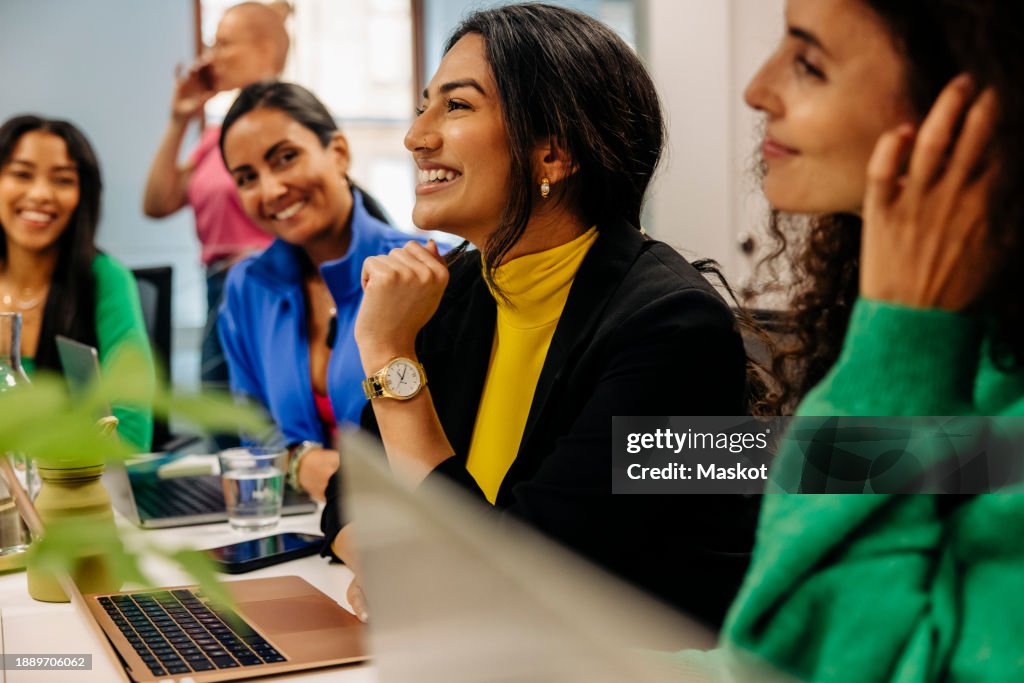 Smiling female business professional with colleagues during meeting at office