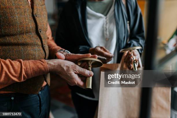 midsection of salesman with candlestick holder standing female customer in store - antique stock pictures, royalty-free photos & images
