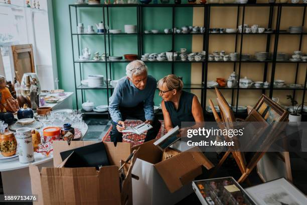 male and female colleagues discussing while sitting in antique shop - small business stock pictures, royalty-free photos & images