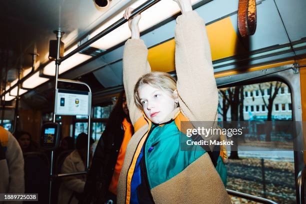 girl holding handle while traveling in tram on weekend - alpha female stock pictures, royalty-free photos & images