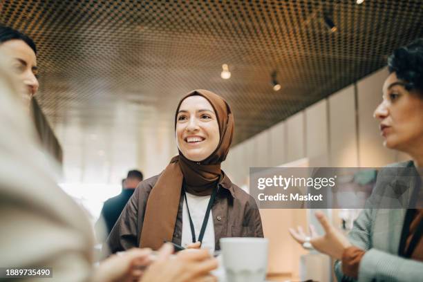 smiling businesswoman wearing hijab and discussing with female corporate professionals during seminar at conference cent - voile religieux photos et images de collection