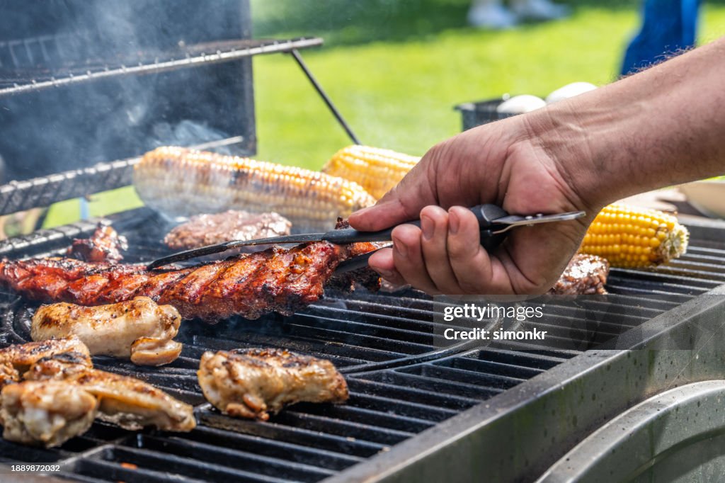 Mann mit Zange, um Fleisch vom Grill zu nehmen