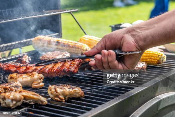 man using tongs to take meat off grill - backyard grilling stock pictures, royalty-free photos & images