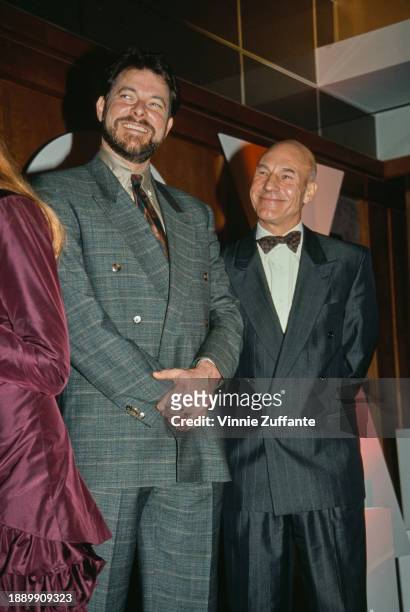 American actor and director Jonathan Frakes, wearing a grey checked double-breasted suit, and British actor Patrick Stewart, who wears a dark grey...