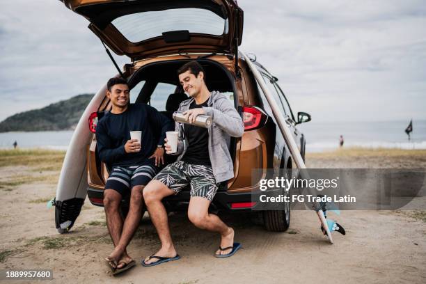 surferfreunde reden und trinken auf dem kofferraum am strand - wonderlust stock-fotos und bilder