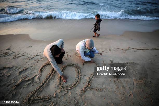 Palestinian girls are writing ''2024'' in the sand during the last sunset of the year in Deir al-Balah, in the central Gaza Strip, on December 31...