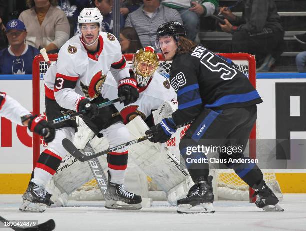 Joonas Korpisalo of the Ottawa Senators watches for a puck in between teammate Travis Hamonic and Tyler Bertuzzi of the Toronto Maple Leafs during...