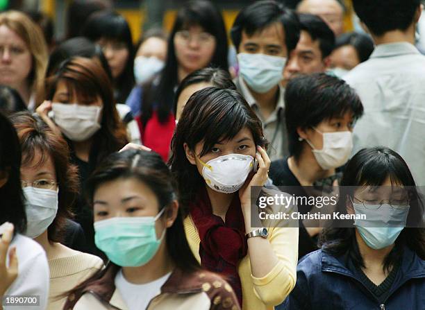 People wear surgical masks to try to reduce the chance of infection from SARS whilst walking through the business district April 1, 2003 in Hong...