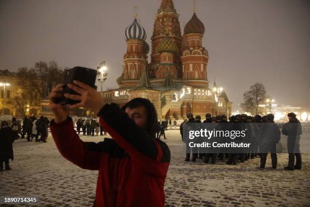 Man takes a selfie photo next to Russian National Guard Service's OMON special unit officers in uniform, on Red Square near the Kremlin on December...