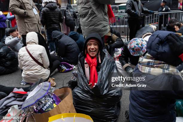 Judyth Leal sits in a black trash bag to keep warm as she waits for the New Year's Eve celebrations in Times Square on December 31, 2023 in New York...