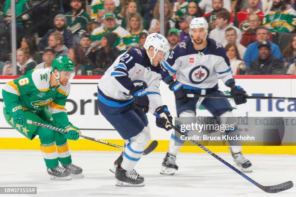 Dominic Toninato of the Winnipeg Jets skates with the puck while Dakota Mermis of the Minnesota Wild defends during the game at the Xcel Energy...