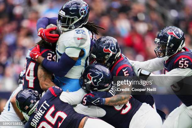 Derrick Henry of the Tennessee Titans is tackled by the Houston Texans during the first half at NRG Stadium on December 31, 2023 in Houston, Texas.