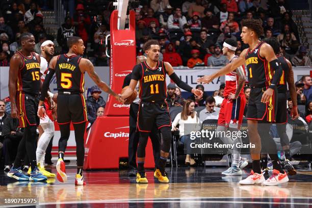 Trae Young, Dejounte Murray and Jalen Johnson of the Atlanta Hawks high five during the game against the Washington Wizards on December 31, 2023 at...