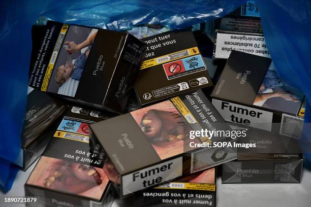 In this photo illustration, loose packets of cigarettes come out of a blue plastic bag. From January 1 most packs of 20 cigarettes will cross the...