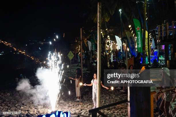 Girl lights fireworks during the New Year's Eve celebration in El Tunco beach on December 31, 2023 in La Libertad, El Salvador.