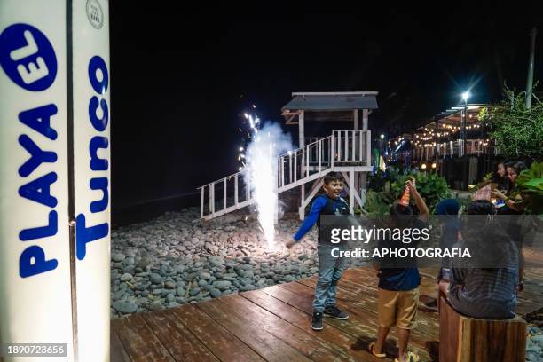 Kids enjoy fireworks during the New Year's Eve celebration in El Tunco beach on December 31, 2023 in La Libertad, El Salvador.