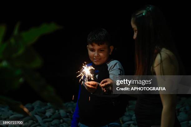 Woman with her son light fireworks during the New Year's Eve celebration in El Tunco beach on December 31, 2023 in La Libertad, El Salvador.