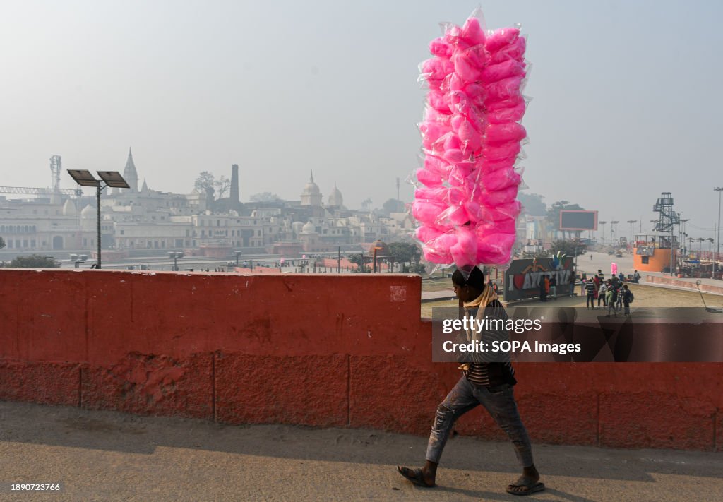 A candy floss seller walks near the banks of the river Saryu...