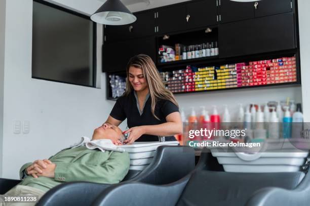 woman is washing a client's hair - newspaper cutting stock pictures, royalty-free photos & images