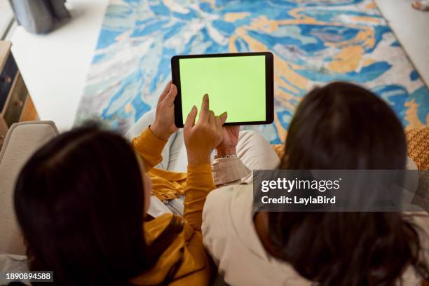zwei frauen sitzen auf einem sofa und benutzen ein tablet - ipad green screen stock-fotos und bilder
