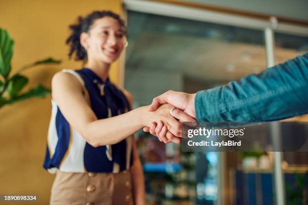 two business people shaking hands in an office, a woman and a man smiling - handshake stock pictures, royalty-free photos & images