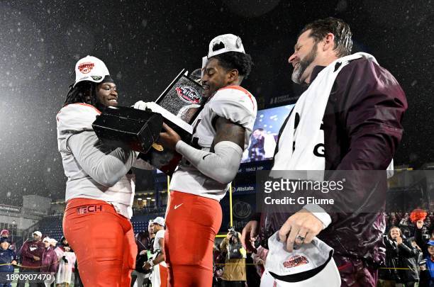 Head coach Brent Pry of the Virginia Tech Hokies celebrates as Norell Pollard and Alan Tisdale hold the trophy after a 41-20 victory against the...