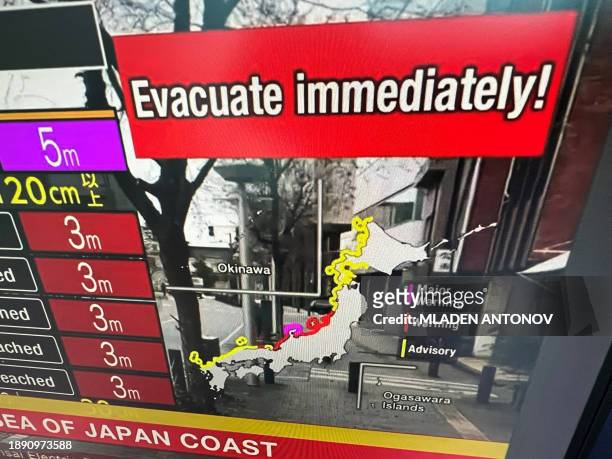This image taken in Hong Kong on January 1, 2024 shows a warning message on a screen from a live feed on NHK World asking people to evacuate from the...