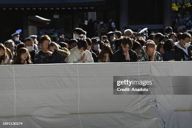 People pray and throw coins to offer prayers for the New Year at the Meiji Shrine on January 1st, 2024 in Tokyo, Japan. Japanese go to Shrine to...