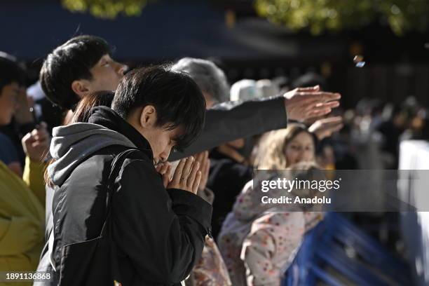 People pray and throw coins to offer prayers for the New Year at the Meiji Shrine on January 1st, 2024 in Tokyo, Japan. Japanese go to Shrine to...