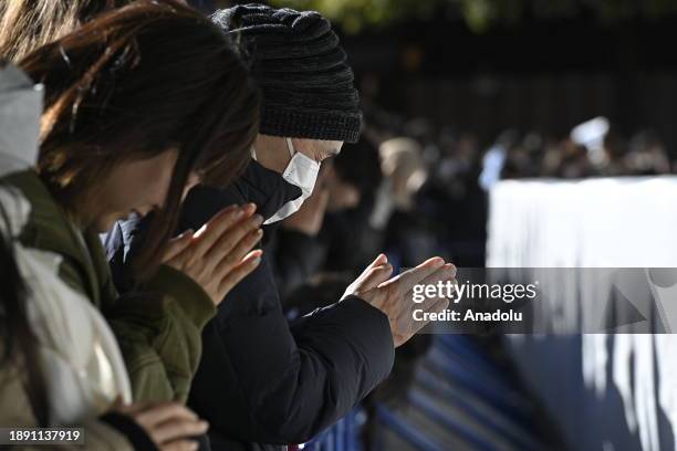 People pray and throw coins to offer prayers for the New Year at the Meiji Shrine on January 1st, 2024 in Tokyo, Japan. Japanese go to Shrine to...