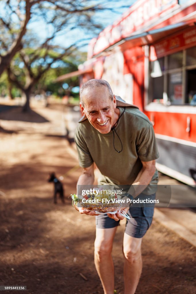 屋台でアサイーボウルを持ちながら微笑む男性