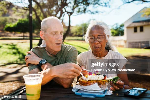 seniorin und ehemann essen açaí-schüssel draußen - hawaiianischer-abstammung stock-fotos und bilder