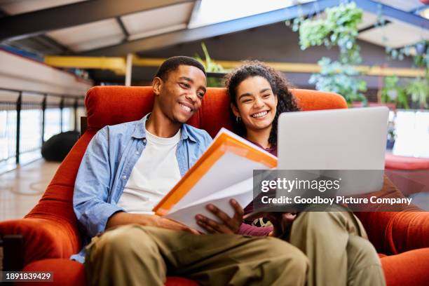 college students smiling while doing homework in a chair in a campus lounge - women laughing stock pictures, royalty-free photos & images