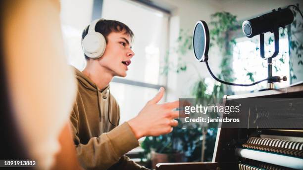 male student wearing headphones practicing singing lessons and woman playing background music on the piano - art and craft stock pictures, royalty-free photos & images