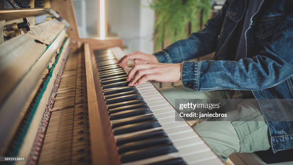 Male student practicing piano lessons and playing on an old school open piano. Close-up hands pressing keys