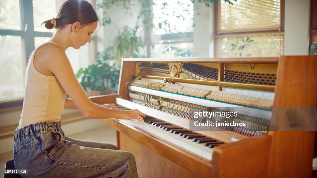 Female student practicing piano lessons. Playing classical music