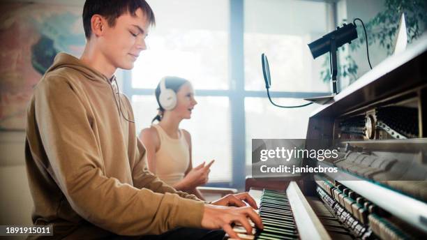female student practicing singing lessons and male student playing background music on the piano - woodies 10 for 16 show stock pictures, royalty-free photos & images