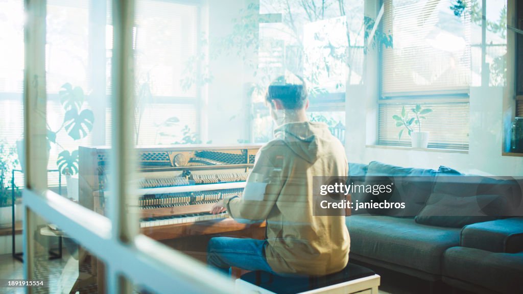Rear view through the window glass male student practicing piano lessons and playing on an old school open piano