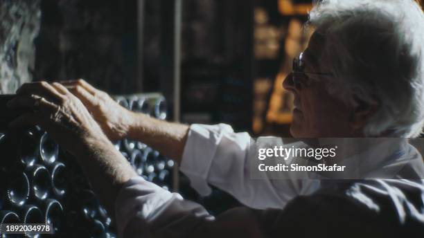 old man wine maker arranging bottles of wine in warehouse -in the wine cellar - sparkling wine stock pictures, royalty-free photos & images