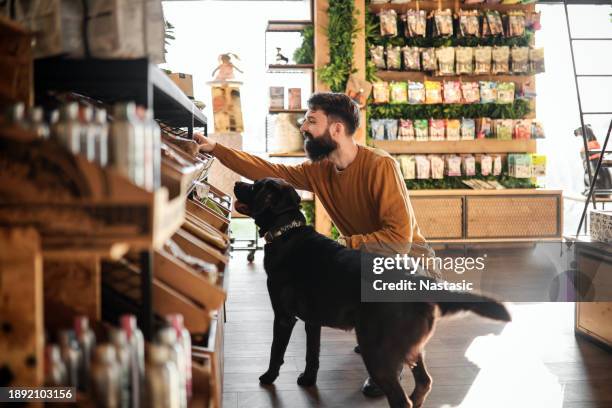 un joven y su cachorro en la tienda de mascotas - tienda de animales domésticos fotografías e imágenes de stock