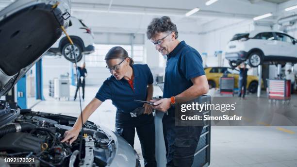 manager e meccanico valutano il motore dell'auto per prestazioni ottimali - meccanico foto e immagini stock