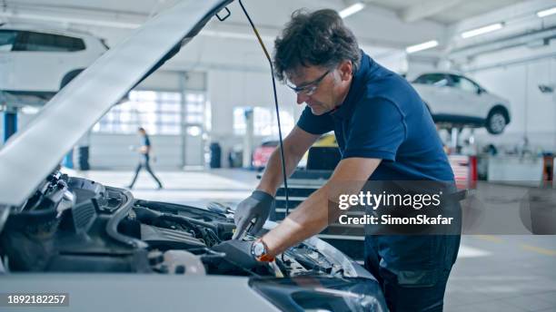 male mechanic working on car engine in auto repair shop - bilverkstad bildbanksfoton och bilder
