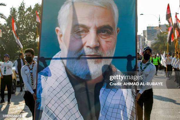 Youth members of the scouting movement walk with a large banner depicting Qasem Soleimani, the slain commander of Iran's Islamic Revolutionary Guard...