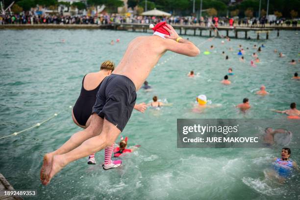 People jump into the water during the traditional New Year's jump into the Adriatic sea in Portoroz, on January 1, 2024.