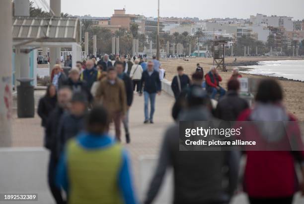 January 2024, Spain, Palma: People walk along the Arenal beach promenade in gloomy weather on New Year's Day. Temperatures on the Spanish island...