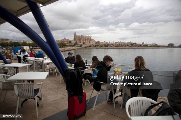 January 2024, Spain, Palma: People sit in a bar by the water in cloudy weather on New Year's Day. Temperatures on the Spanish island reached a mild...