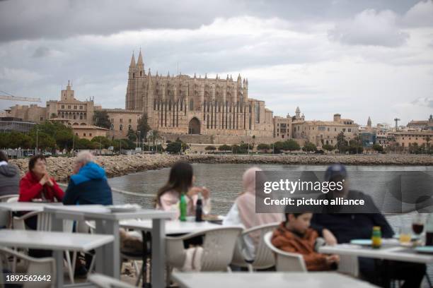 January 2024, Spain, Palma: People sit in a bar by the water in cloudy weather on New Year's Day. Temperatures on the Spanish island reached a mild...