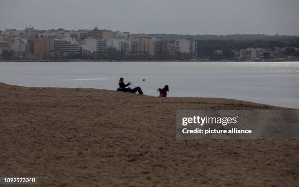 January 2024, Spain, Palma: People play with a ball on the beach in Arenal in cloudy weather on New Year's Day. Temperatures on the Spanish island...