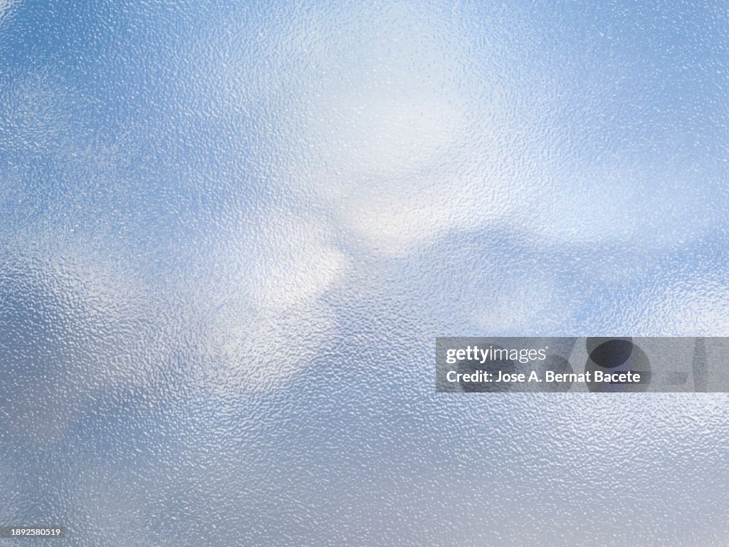 Abstract background, translucent glass visual effect with blue sky and clouds.