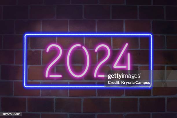 neon sign saying '2024' against dark brick wall background - escrita ocidental imagens e fotografias de stock